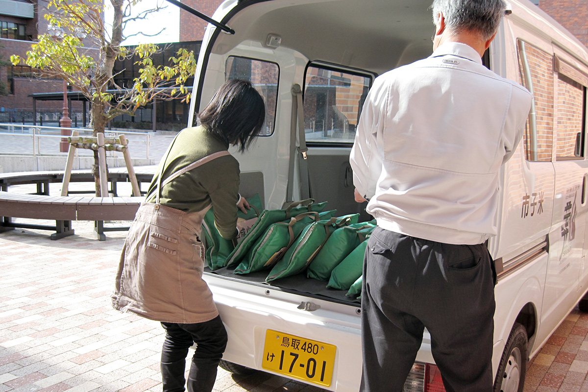 公用車に袋を載せる